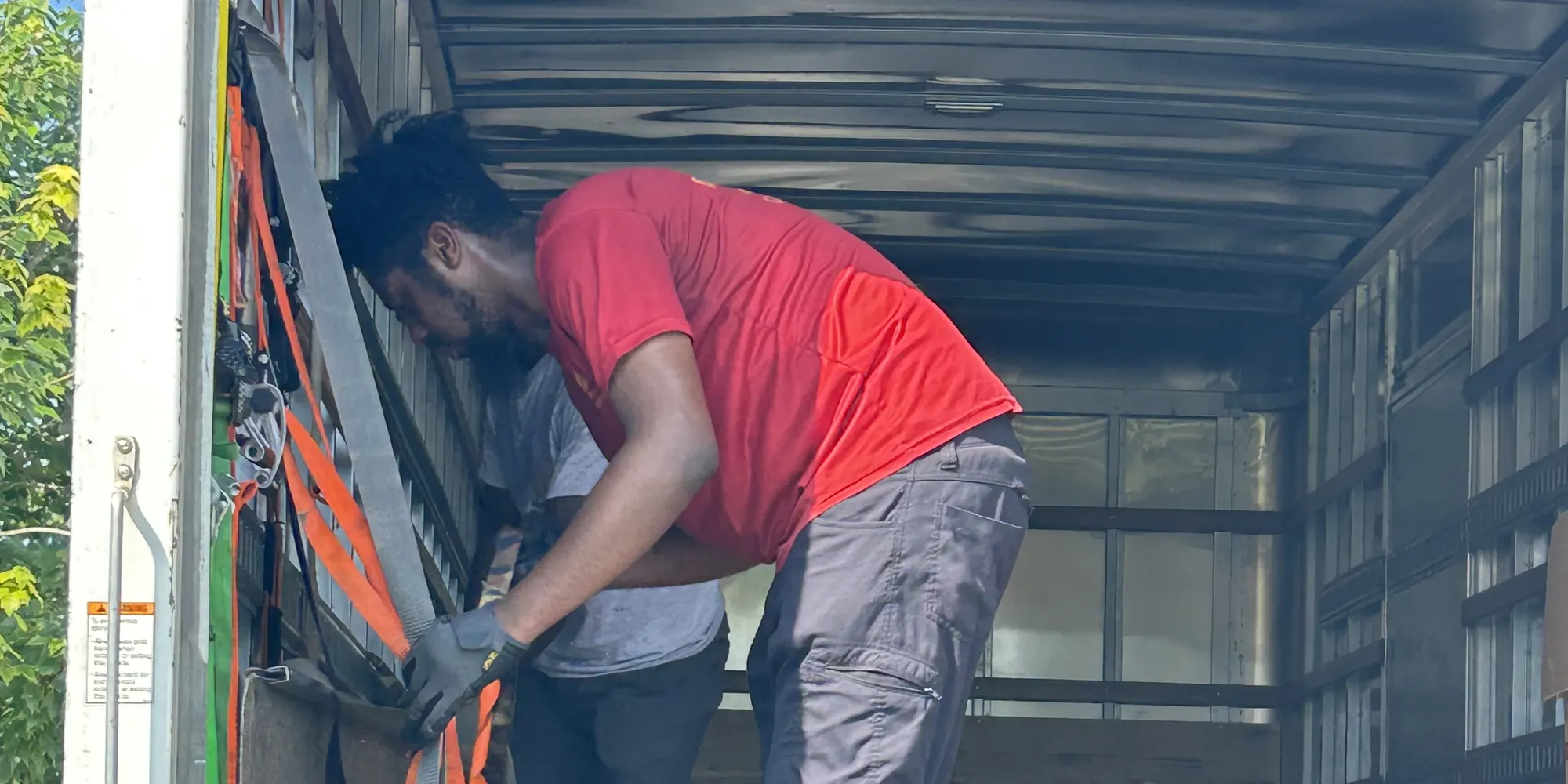 Quest crew member securing a load with straps inside a box truck