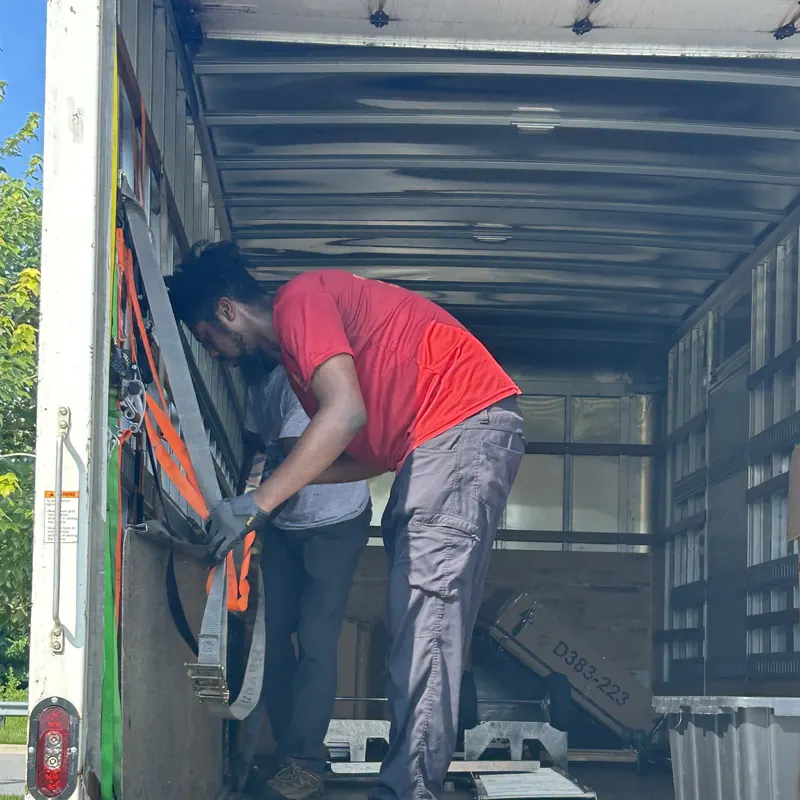 Crew member strapping a load inside a box truck